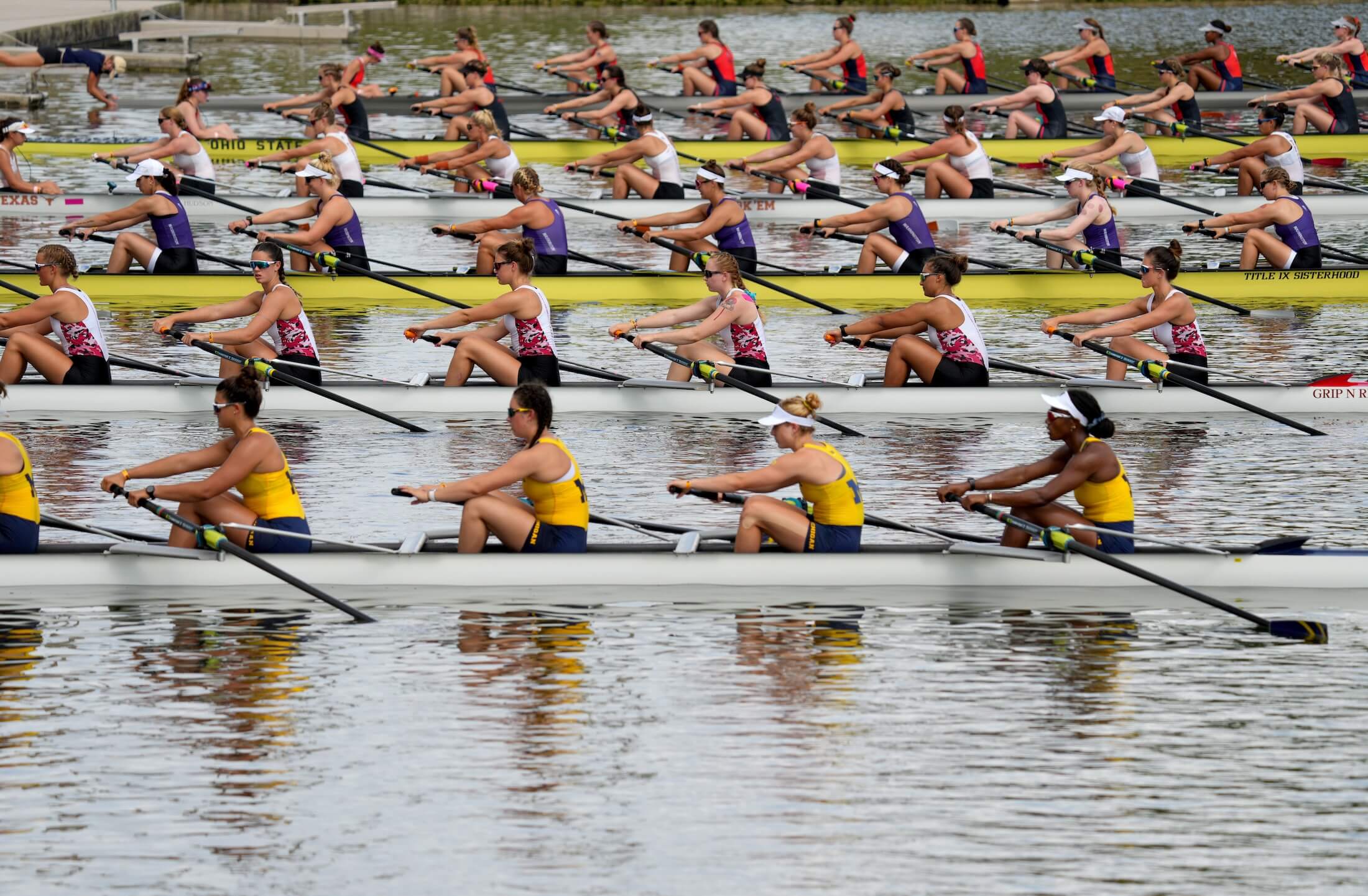 Collegiate rowing teams in action, the nearest team is the University of Michigan woment's rowing team.